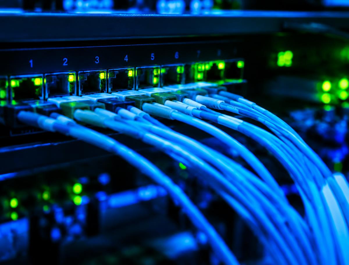 Fiber optic cables connected to a network switch with glowing status lights